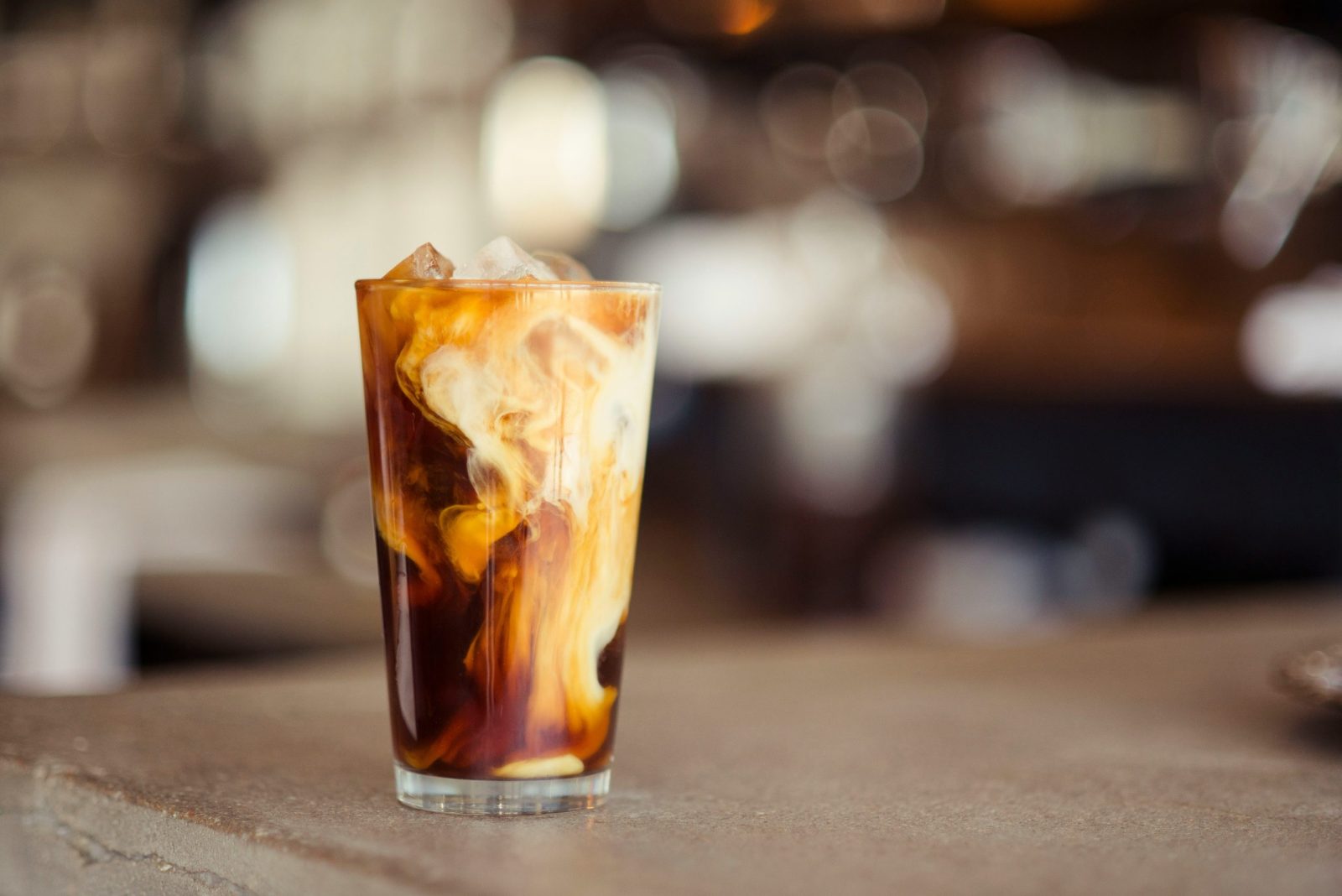 Two glasses of nitro cold brew with milk being poured